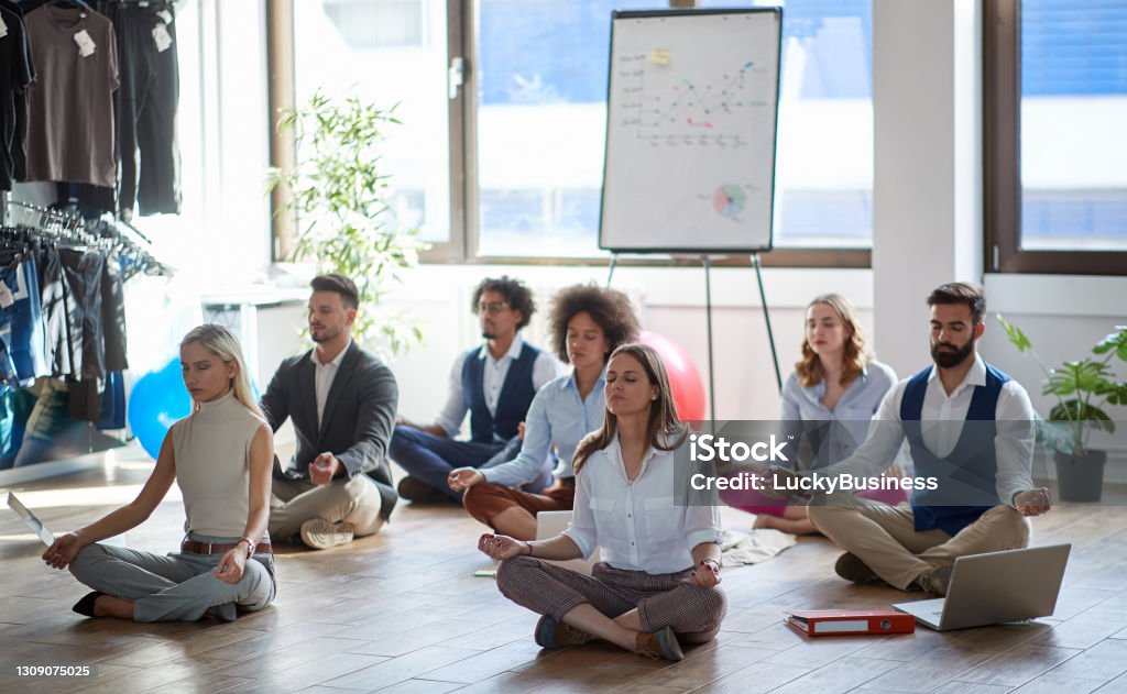 group of business colleagues meditating at work, sitting on the floor. modern, business, meditation concept